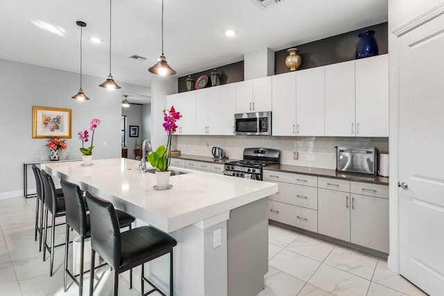 kitchen featuring a center island with sink, white cabinetry, and appliances with stainless steel finishes