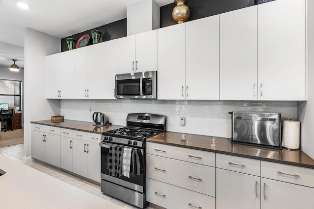 kitchen featuring white cabinets, decorative backsplash, ceiling fan, and stainless steel appliances