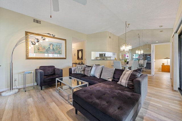 living area with vaulted ceiling, light wood finished floors, visible vents, and baseboards