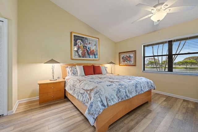 bedroom featuring light wood-type flooring, vaulted ceiling, baseboards, and ceiling fan