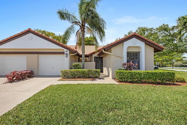 mediterranean / spanish home featuring an attached garage, driveway, a front lawn, and stucco siding