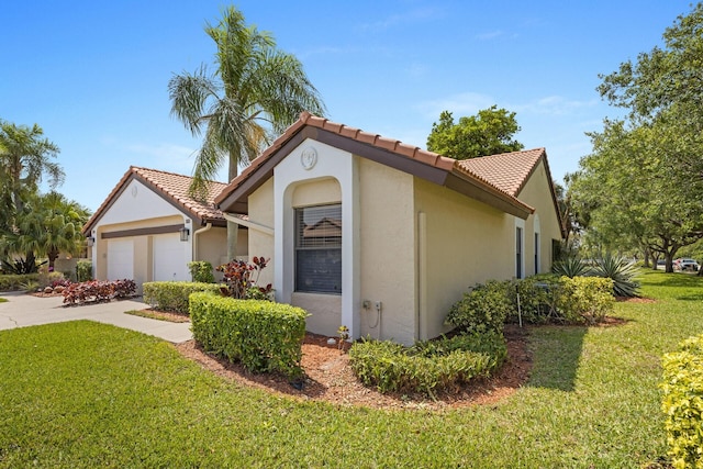 mediterranean / spanish-style home with a garage, driveway, a tile roof, a front yard, and stucco siding