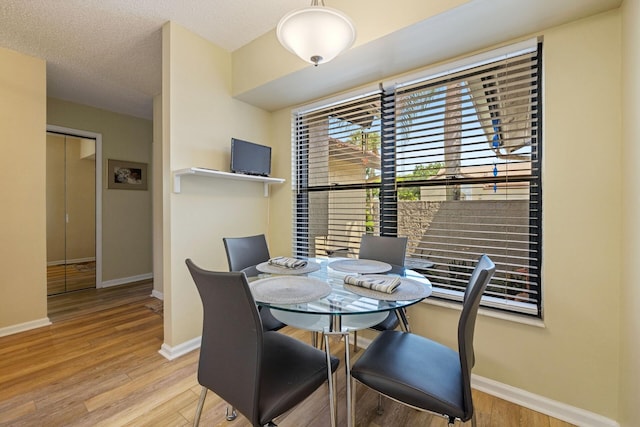 dining room featuring light hardwood / wood-style flooring and a textured ceiling