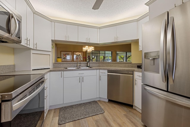 kitchen featuring white cabinets, light wood-style flooring, stainless steel appliances, and a sink