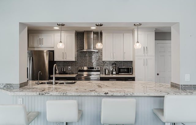 kitchen featuring appliances with stainless steel finishes, a breakfast bar area, wall chimney exhaust hood, and sink