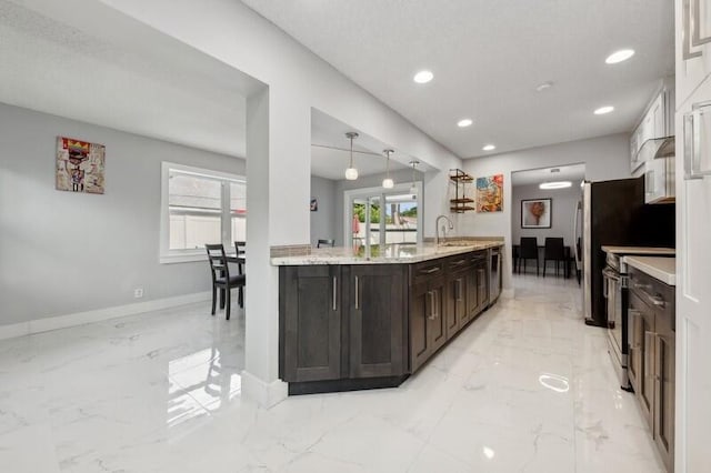 kitchen with dark brown cabinetry, light stone countertops, sink, decorative light fixtures, and stainless steel range with electric cooktop