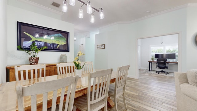 dining space with wood-type flooring, an inviting chandelier, and ornamental molding