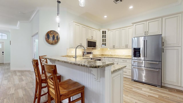 kitchen featuring kitchen peninsula, light stone countertops, ornamental molding, stainless steel appliances, and light hardwood / wood-style floors