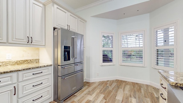 kitchen featuring high quality fridge, crown molding, white cabinets, and light stone counters