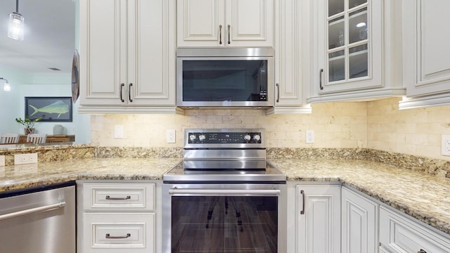 kitchen featuring white cabinets, decorative light fixtures, and stainless steel appliances