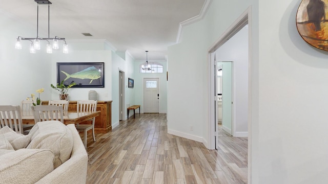 hall featuring crown molding, light hardwood / wood-style flooring, and a chandelier