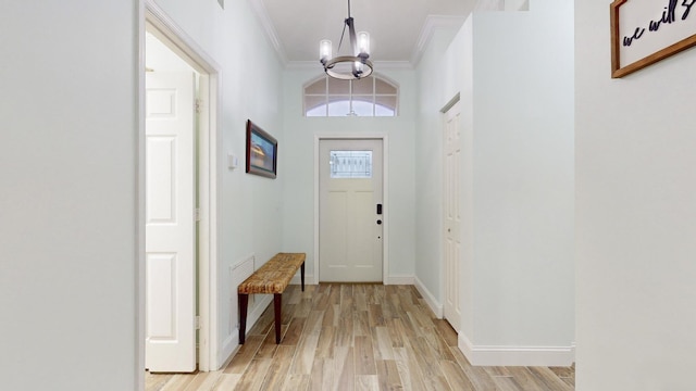 entryway with light wood-type flooring, an inviting chandelier, and crown molding