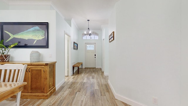 entryway featuring a chandelier, light hardwood / wood-style floors, and crown molding