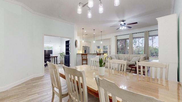 dining room with a healthy amount of sunlight, light hardwood / wood-style floors, and crown molding