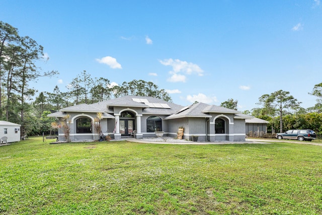 view of front facade featuring french doors, a front yard, and solar panels