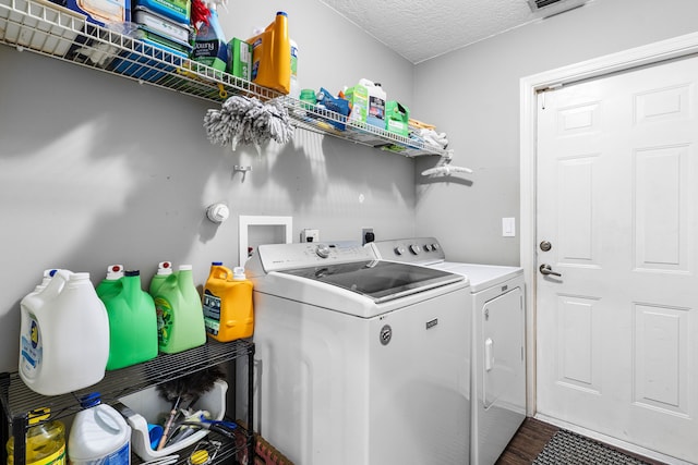 washroom featuring a textured ceiling, dark hardwood / wood-style floors, and washing machine and clothes dryer