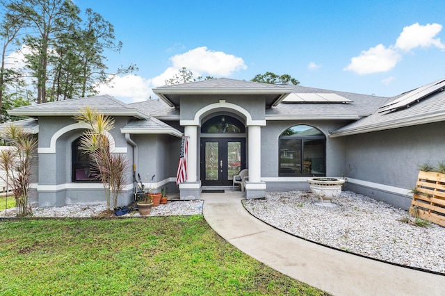 entrance to property featuring french doors, a yard, and solar panels