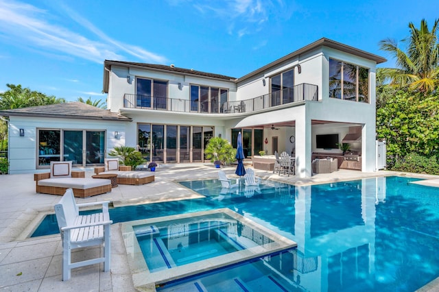 rear view of house with a balcony, a patio, and a pool with hot tub