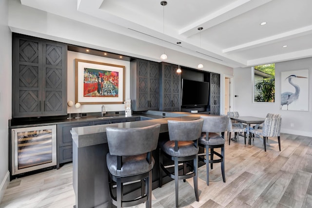 bar featuring beverage cooler, sink, light hardwood / wood-style flooring, gray cabinets, and hanging light fixtures