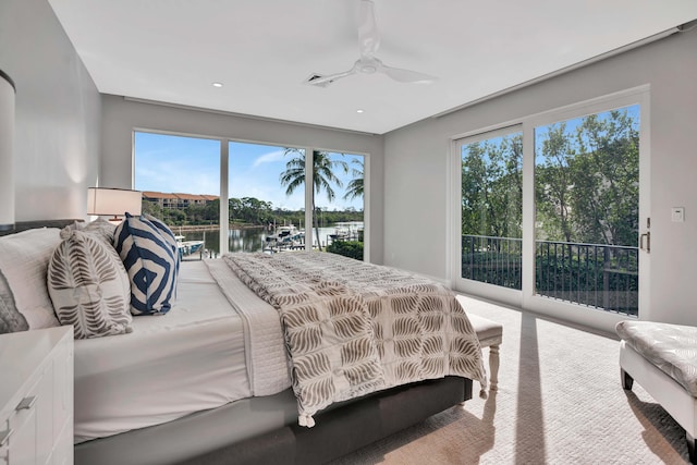 carpeted bedroom featuring access to outside, a water view, and ceiling fan