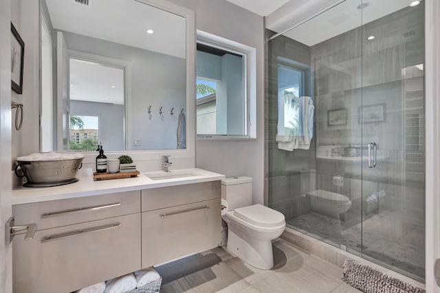 bathroom featuring tile patterned floors, vanity, a shower with shower door, and toilet