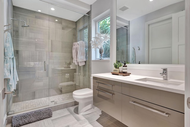 bathroom featuring tile patterned floors, vanity, a shower with shower door, and toilet