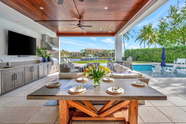 view of patio / terrace with an outdoor living space, a fenced in pool, a water view, sink, and ceiling fan