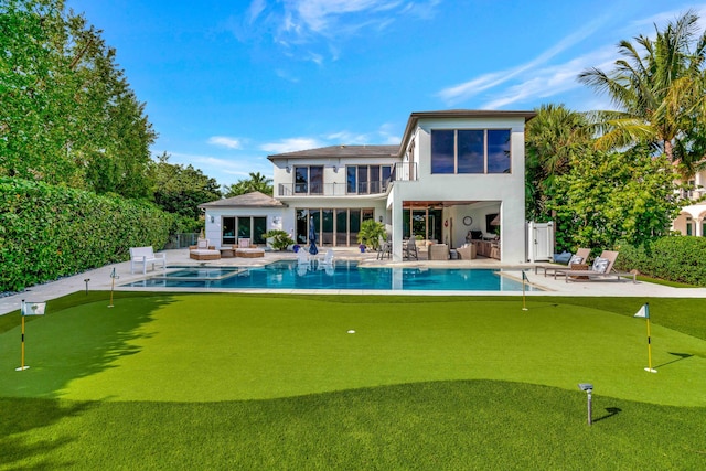 back of property featuring an outdoor kitchen, a balcony, a fire pit, a patio, and a fenced in pool