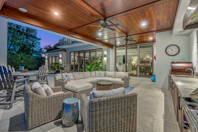 patio terrace at dusk featuring ceiling fan and an outdoor hangout area