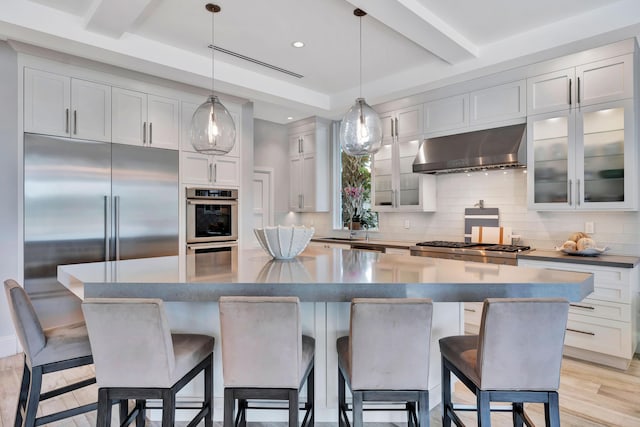 kitchen with a kitchen bar, a large island, hanging light fixtures, and exhaust hood