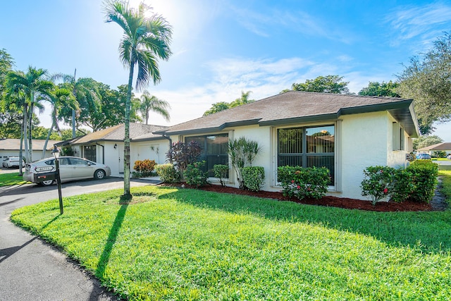 single story home featuring a front lawn and a garage