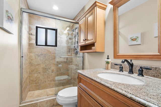 bathroom featuring a shower with door, vanity, and toilet