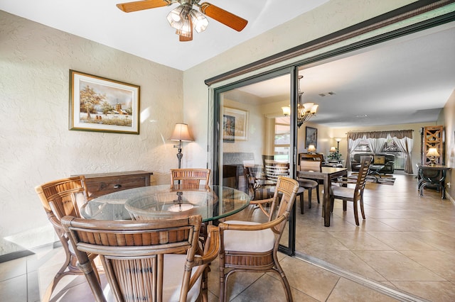 tiled dining area featuring ceiling fan with notable chandelier