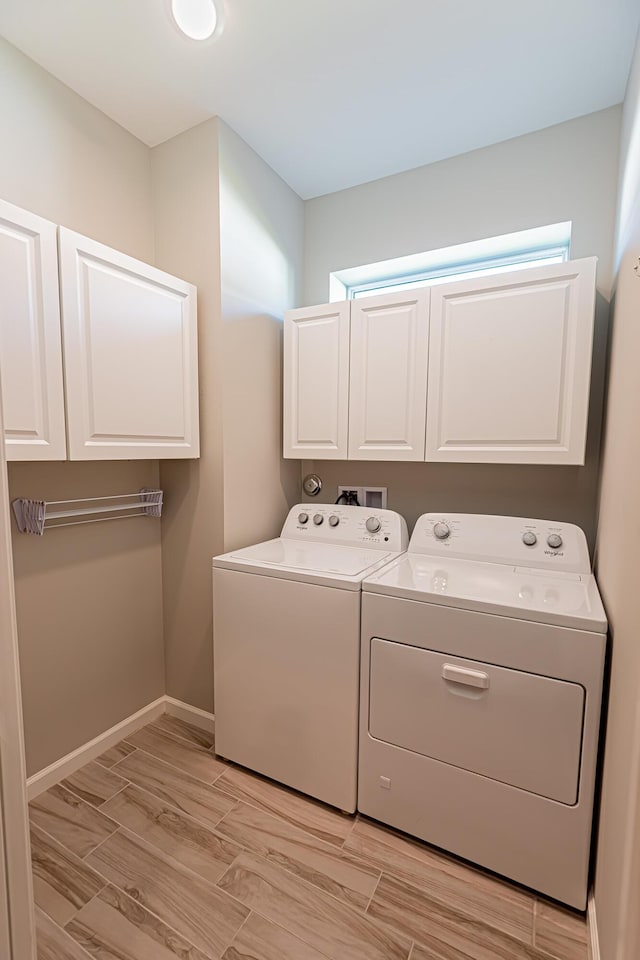 laundry room featuring cabinets, washer and clothes dryer, and light hardwood / wood-style flooring