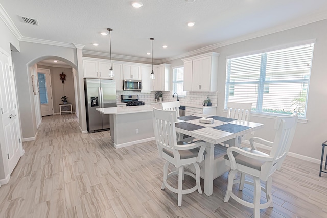 dining area with ornamental molding and light hardwood / wood-style floors