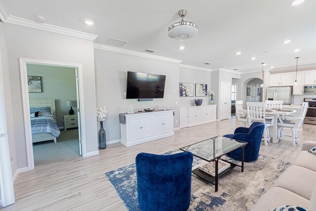 dining room with light wood-type flooring, ornamental molding, and a textured ceiling