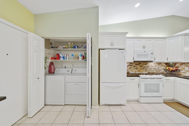 kitchen featuring washing machine and dryer, lofted ceiling, white cabinets, and white appliances