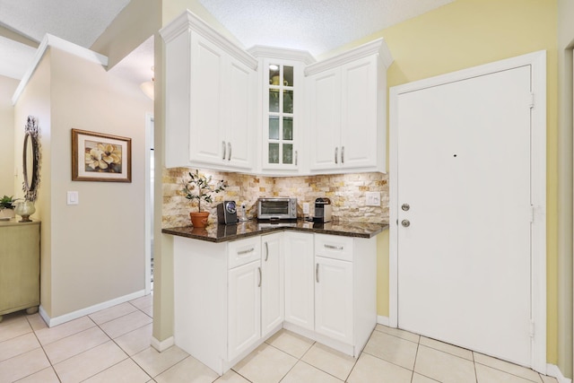 kitchen featuring white cabinets, a textured ceiling, dark stone countertops, and light tile patterned flooring