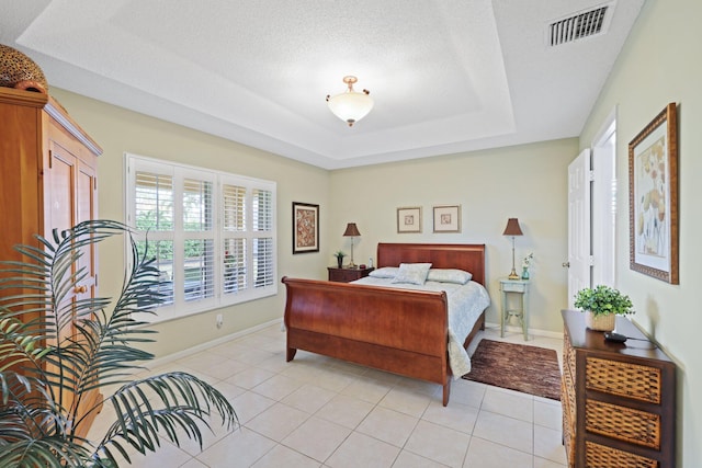 tiled bedroom featuring a textured ceiling and a raised ceiling