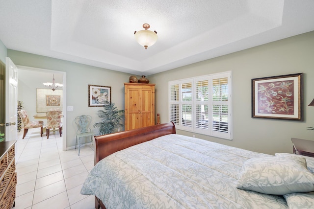 tiled bedroom with a tray ceiling, a chandelier, and a textured ceiling