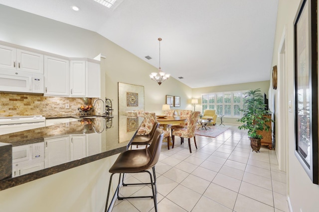 kitchen with white cabinetry, sink, tasteful backsplash, lofted ceiling, and decorative light fixtures