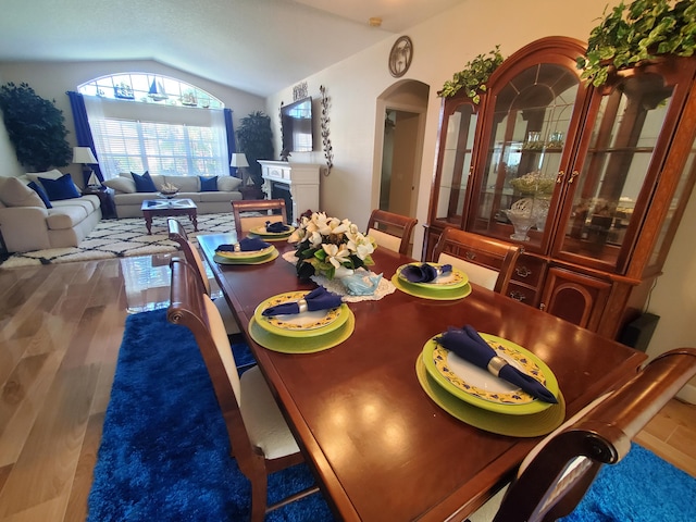 dining space with wood-type flooring and vaulted ceiling