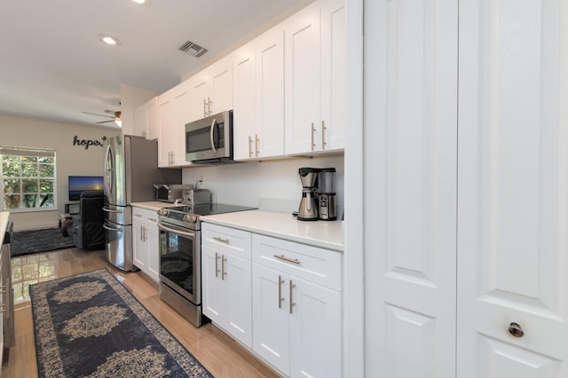 kitchen featuring white cabinets, light wood-type flooring, stainless steel appliances, and ceiling fan