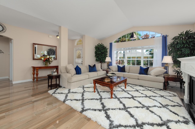 living room with light hardwood / wood-style flooring, a fireplace, and vaulted ceiling