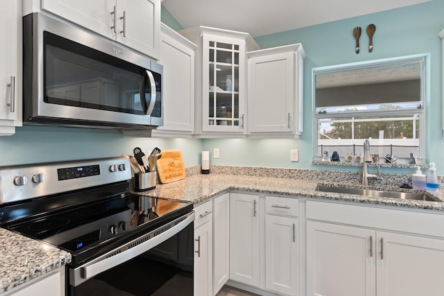 kitchen featuring white cabinetry, sink, light stone counters, and appliances with stainless steel finishes