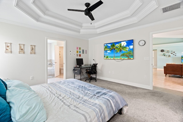 carpeted bedroom featuring a tray ceiling, connected bathroom, ceiling fan, and ornamental molding