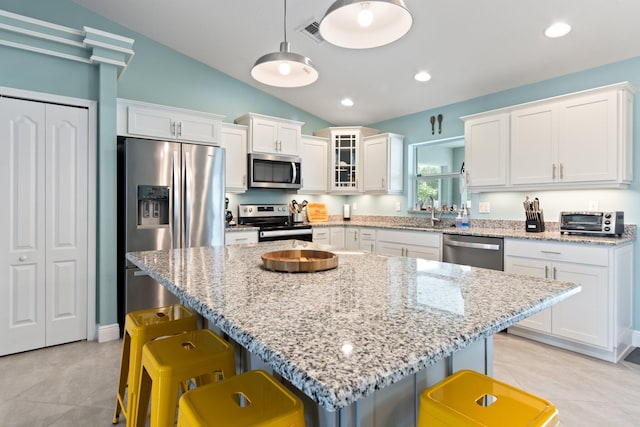 kitchen featuring decorative light fixtures, lofted ceiling, stainless steel appliances, and a breakfast bar