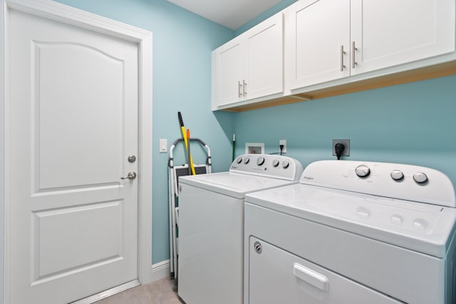 laundry area with washing machine and clothes dryer, light tile patterned floors, and cabinets