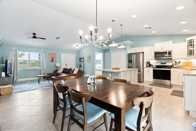 tiled dining room with ceiling fan with notable chandelier and vaulted ceiling