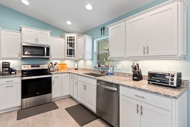 kitchen featuring sink, white cabinets, vaulted ceiling, and appliances with stainless steel finishes